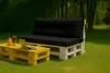 A pallet sofa and coffee table set with cushions, placed on a grassy lawn in a garden setting. Anteprima dell’immagine prodotto
