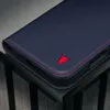 A close-up shot of a dark blue leather phone case with red stitching and a red bull logo. Voir les images du produit