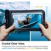 A person is holding a waterproof phone case with a phone inside, showing a surfer in the water. Náhľad obrázku produktu