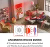 A man is relaxing on a sofa in a living room, using a laptop, while an infrared heater is shown mounted on the wall, emitting red heat waves. Produktbild-Vorschau