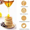 A honey dispenser pouring honey onto a stack of pancakes, with berries on the side. To the right are icons and text describing product features. Produktbild-Vorschau