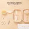 A flat lay of a baby care kit laid out on a wooden surface, with some items inside an open case. Produktbild-Vorschau