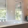 A bathroom with a bathtub and windows with roller shutters. Produktbild-Vorschau