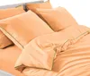 A close-up view of a peach-colored duvet cover and pillowcases with green trim, neatly arranged on a bed. Produktbild-Vorschau