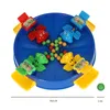 A top-down view of a children's board game with four frog-shaped game pieces and colorful marbles on a blue circular board. Náhled obrázku produktu