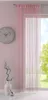 A room interior with a window covered by a pink string curtain, a clock on the wall, and a vase with branches on a table. Produktbild-Vorschau