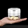 A hand holding a mini electric garlic chopper with garlic cloves inside. Náhľad obrázku produktu