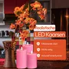A kitchen counter with a vase of artificial flowers and three pink LED candles. Produktbild-Vorschau