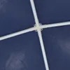 A close-up view of a white plastic connector with four white poles attached, set against a dark blue textured background. Náhled obrázku produktu
