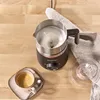 A milk frother is shown on a wooden table next to a cup of coffee. Produktbild-Vorschau