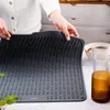 A person's hands are holding a gray silicone dish drying mat over a countertop. Náhľad obrázku produktu