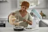 A woman is using a stand mixer in a kitchen. Produktbild-Vorschau