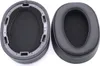 Two black ear pads for headphones are shown against a white background. One ear pad is shown from the inside, revealing the foam padding and mounting mechanism. The other ear pad is shown from the outside, displaying its smooth, cushioned surface. Náhled obrázku produktu