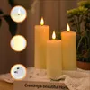 Three LED candles with flickering flames are arranged on a white lace cloth, with a blurred green plant in the background. Insets show close-ups of the candle flame, the illuminated candle body, and the battery compartment. Voir les images du produit
