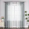 A window with sheer curtains and a small table with a vase of flowers and a framed picture. Produktbild-Vorschau