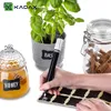 A hand is writing on a chalk label with a chalk marker, next to a jar of honey, a potted plant, and a jar of cinnamon sticks. Produktbild-Vorschau