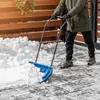 A person is using a blue snow shovel to clear snow from a paved area. Podgląd zdjęcia produktu