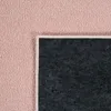 A close-up view of the corner of a pink rug, showing the texture of the pile and the dark gray backing. Produktbild-Vorschau