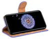 A smartphone in a blue and brown flip case, displaying a dandelion image on its screen. Náhľad obrázku produktu