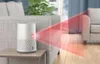 A white cylindrical device with perforated sides sits on a small wooden table, projecting a red beam of light across a living room setting. Podgląd zdjęcia produktu