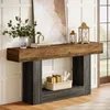 A console table with decorative items on top and a basket with books on the shelf below, placed against a paneled wall with a window in the background. Anteprima dell’immagine prodotto