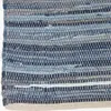 A close-up view of a woven rug made from strips of denim fabric. Náhled obrázku produktu