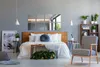 A bedroom scene with a bed, chair, and shelving unit. Produktbild-Vorschau