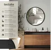 A round mirror is displayed on a wall above a wooden cabinet, with decorative items on the cabinet. Produktbild-Vorschau