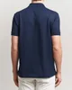 A person wearing a dark blue polo shirt. Produktbild-Vorschau