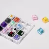 A collection of mechanical keyboard switches arranged in a clear plastic tray, with a few switches scattered around the tray. Produktbild-Vorschau