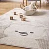 A close-up of a children's rug with a bear face design, featuring wooden alphabet blocks scattered on it. Produktbild-Vorschau