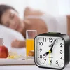 A woman sleeping in bed with a breakfast tray and an alarm clock in the foreground. Produktbild-Vorschau