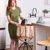 A woman is placing a small appliance into a tote bag in a kitchen setting. Anteprima dell’immagine prodotto