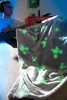 A person wearing headphones is sitting in a chair, covered by a blanket with a Minecraft Creeper pattern. The blanket is glowing in the dark. Podgląd zdjęcia produktu