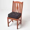 A black seat cushion placed on a wooden chair. Anteprima dell’immagine prodotto