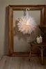 A white paper star lantern hangs in a large wooden frame, with two lit candles on a wooden chair to the right. Podgląd zdjęcia produktu