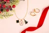 A flat lay of Christmas-themed jewelry with a sprig of holly and a red ribbon. Anteprima dell’immagine prodotto