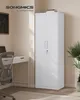 A white metal storage cabinet is shown in a room with a desk and chair. Náhled obrázku produktu