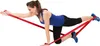 A woman is performing a fitness exercise using a red resistance band. Produktbild-Vorschau