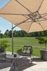 An outdoor patio scene with a large cantilever umbrella providing shade over a seating area with chairs and a table. Produktbild-Vorschau