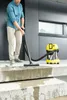 A man is vacuuming wet concrete steps outside a modern building with a Kärcher wet/dry vacuum cleaner. Produktbild-Vorschau