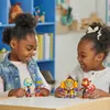 Two young girls are playing with action figures on a table. Podgląd zdjęcia produktu