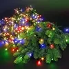 A close-up shot of a string of colorful LED lights intertwined with artificial fir branches. Produktbild-Vorschau