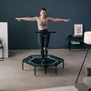 A woman is exercising on a trampoline in a room. Voir les images du produit