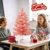 Two children are sitting at a table with a pink Christmas tree and gifts. Anteprima dell’immagine prodotto