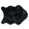 A black, irregularly shaped rug with a fluffy texture is shown against a white background. Produktbild-Vorschau