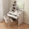 A white vanity table with a mirror and drawers, filled with makeup and accessories, next to a white chair. Produktbild-Vorschau