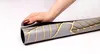 A hand is shown holding a rolled-up radiator cover with a leaf pattern. Produktbild-Vorschau