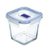 A clear glass food storage container with a blue lid is shown against a white background. Produktbild-Vorschau