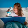 A young girl is reading a book in bed at night, illuminated by a toy flashlight. Produktbild-Vorschau